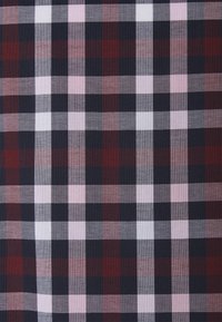 Tessuto di cotone con un motivo a quadri in rosso scuro, blu navy, rosa e bianco. La texture è tessuta con una finitura liscia.