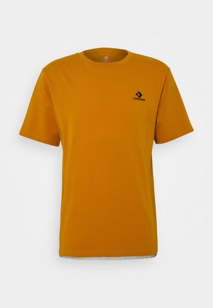 T-shirt jaune moutarde en coton. Doté de manches courtes et d'un col rond. Petit logo noir sur le coin supérieur gauche de la poitrine.