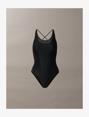 Black one-piece swimsuit with a geometric texture, featuring a deep neckline and crisscross straps at the back. Smooth fabric.