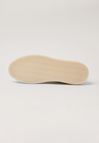 Gumowa podeszwa zewnętrzna o fakturze jodełki, jasnobeżowy kolor, gładkie krawędzie oraz subtelne detale marki.