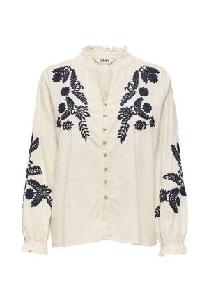 Blouse crème à manches longues avec broderie florale noire sur les épaules et les manches, col et poignets à volants, et boutons recouverts de tissu sur le devant.