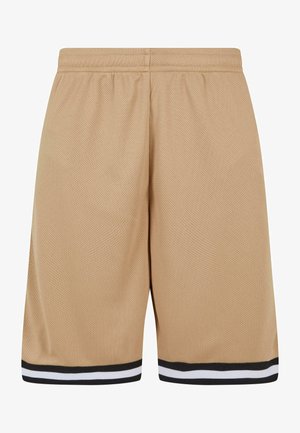 Witte korte mouw T-shirt gecombineerd met beige mesh shorts met zwart-witte strepen langs de zoom, aangevuld met witte sneakers.