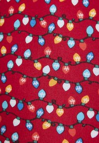 Tela roja con un patrón repetido de luces navideñas coloridas en azul, amarillo, blanco y naranja, conectadas por hilos de color verde oscuro.