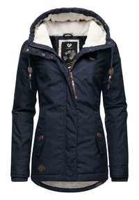 Veste bleu marine avec doublure en fausse fourrure et capuche, dotée de quincaillerie marron, fermeture éclair et poches latérales. Texture lisse, design chaud.