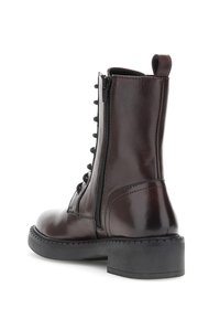 Stivale alla caviglia in pelle marrone scuro con cerniera laterale, lacci neri, fondo per il pull tab e suola e tacco in gomma nera chunky.