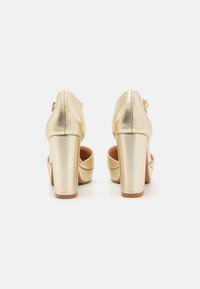 Gold metallic high heel shoes with a round toe, platform front, and chunky heel; smooth texture with a glossy finish and ankle strap detail.
