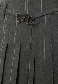 Tessuto grigio plissettato con righe bianche, caratterizzato da una fibbia metallica nera a forma di "M" sulla cintura.