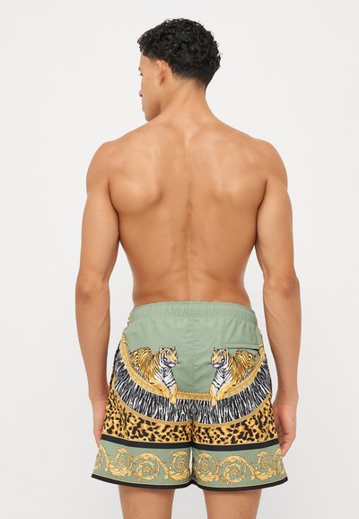 Grønne svømmedragtshorts med tiger- og leopardmønstre, elastisk talje og kontrastfarvet sort kant ved benåbningerne.