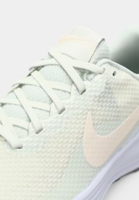 Ανοιχτό πράσινο αθλητικό παπούτσι Nike με υφασμάτινο επάνω μέρος με υφή, κορδόνια σε ταιριαστό χρώμα και ροζ λογότυπο swoosh στο πλάι.