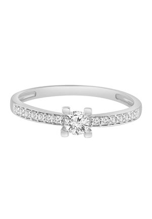 Bague en argent avec un diamant central rond tenu par quatre griffes et des diamants plus petits incrustés le long de l’anneau de chaque côté.