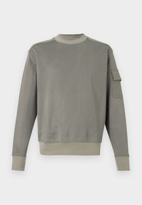 Γκρι φούτερ με μακριά μανίκια, στρογγυλή λαιμόκοψη και τσέπη στο αριστερό μανίκι. Απαλή υφή, ριμπ μανσέτες και λεπτομέρεια στο τελείωμα.