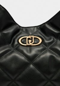 Zwarte gewatteerde leren tas met een gouden ovale sluiting met een verstrengeld ontwerp en zichtbare stikseldetails op het oppervlak.