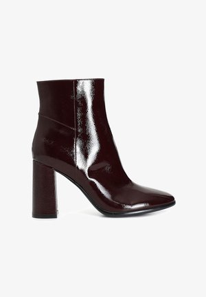 Burgundy patent leather ankle boot with a pointed toe and textured block heel. Smooth surface and sleek design.