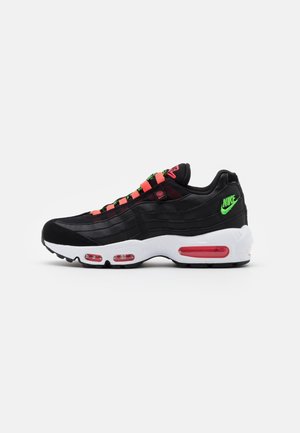 Baskets Nike Air Max 95 noires avec des accents rouges, en matériaux mesh et cuir, semelle intermédiaire blanche et amorti visible dans des coussins rouges.