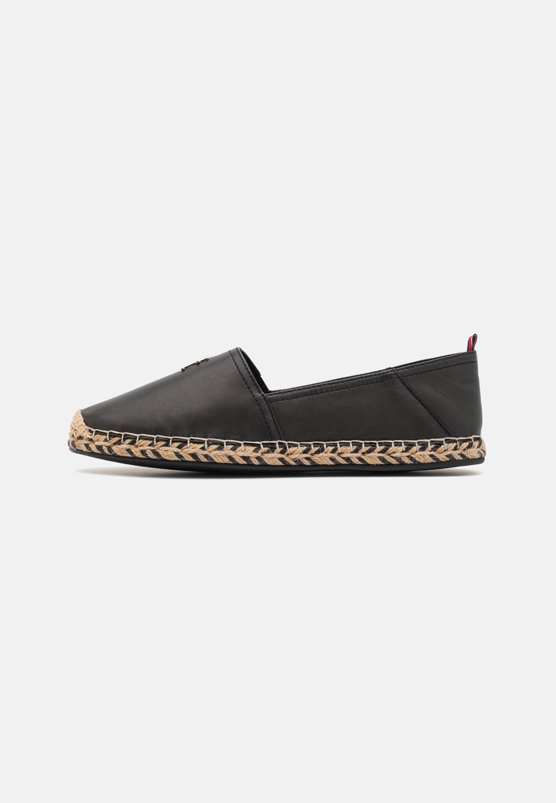 Černá kožená slip-on bota s plochou, espadrilkovou tkanou juteovou podrážkou a kontrastním tmavým prošíváním. Minimalistický design, bez ozdob.