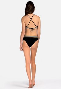 Czarny bikini z krzyżującymi się ramiączkami na plecach, z poziomymi kremowymi i brązowymi paskami przy brzegu. Gładki, elastyczny materiał.