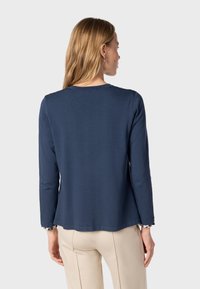 Navy long-sleeve top in soft fabric with a round neckline. Features patterned cuffs and a relaxed fit, detailed stitching at the hem.