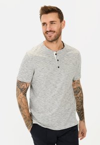 T-shirt henley gris clair à manches courtes avec des rayures subtiles, trois boutons noirs au niveau du col, et une coupe décontractée.