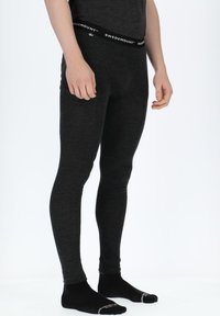 Schwarze thermische Leggings mit enganliegendem Design und elastischem Bund mit Logo. Das Material wirkt glatt und leicht.