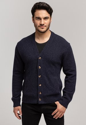 Granatowy wełniany kardigan z dekoltem w serek, z drewnianymi guzikami, ściągaczami u rękawów i bocznymi kieszeniami. Zrobiony na drutach z dopasowaną sylwetką.