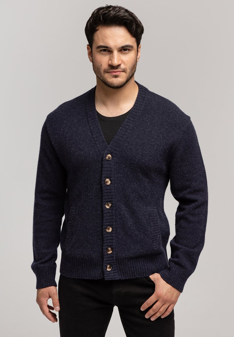 Granatowy wełniany kardigan z dekoltem w serek, z drewnianymi guzikami, ściągaczami u rękawów i bocznymi kieszeniami. Zrobiony na drutach z dopasowaną sylwetką.