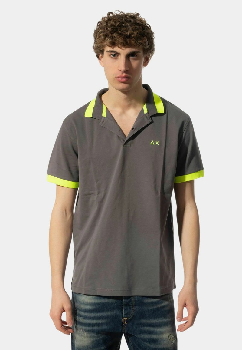 Polo grigio con accenti giallo neon sul colletto e sulle maniche. Realizzato in tessuto liscio, presenta una vestibilità comoda e un colletto parzialmente abbottonato.