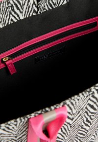 Plátěná taška s zebrovým vzorem a černým vnitřkem. Obsahuje růžovou kapsu na zip a růžovo-šedé pruhované rukojeti.