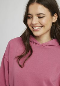 Haut à capuche fuchsia en mélange de coton doux avec une coupe décontractée, doté d'une capuche et d'épaules tombantes, agrémenté de détails de couture subtils.