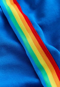 Material albastru prezintă un design cu dungi colorate în roșu, portocaliu, galben, verde și albastru, țesute transversal, creând un model texturat.