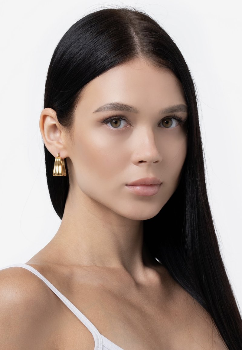 Kultatiput, joissa on viistetty muotoilu, roikkuvat korvalehdestä. Ne ovat kiiltäviä ja sileäpintaisia.