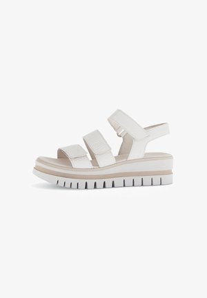 White platform sandals with three adjustable straps, textured material, and a solid sole featuring ridged detailing and a beige accent.