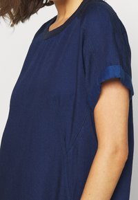 Navyblauwe katoenen t-shirt met opgerolde mouwen, met een ronde hals en subtiele naaddetails. Zachte textuur met een relaxte pasvorm.