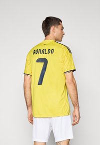 Yellow sports jersey with "RONALDO" and number "7" in blue on the back. Short sleeves, lightweight fabric, textured details.