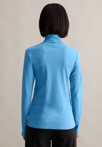 Blauer Langarm-Turtleneck aus weichem, dehnbarem Stoff. Verfügt über ein enganliegendes Design mit hohem Kragen und glatter Textur.