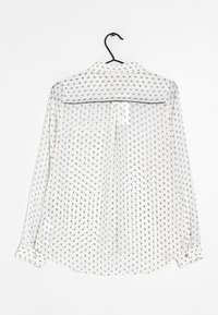 Biała, przezroczysta koszula z długim rękawem, zdobiona powtarzającym się czarnym wzorem kwiatowym, z zapięciem na guzy przy mankietach oraz zaokrąglonym dołem. Posiada detal z tyłu w postaci karczku.