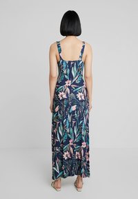 Maxi sukienka w kwiatowy wzór na granatowym tle, regulowane ramiączka, zwiewny materiał, z różowymi i zielonymi motywami roślinnymi.