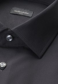 Czarna koszula z kołnierzem o wyraźnej konstrukcji, zapinana na guziki, o gładkim, matowym wykończeniu. Metka z napisem „seidensticker uno”.