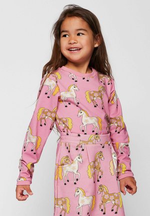 Ružičasta haljina s dugim rukavima s printom jednoroga u žutoj i bijeloj boji, dizajnirana s naglašenim strukom i džepovima.