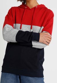 Felpa con cappuccio rossa, grigia e blu navy con design a blocchi di colore. Presenta maniche lunghe, cappuccio con coulisse e tasca frontale. Realizzata in morbido tessuto misto cotone.