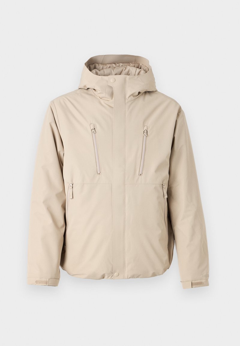 Chaqueta impermeable beige con capucha, que cuenta con dos bolsillos en el pecho con cremallera y un corte recto. Textura suave, puños ajustables.