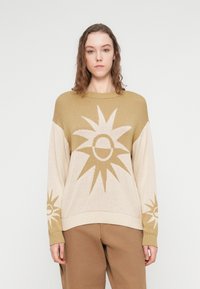 Πλεκτό πουλόβερ σε μπεζ και ελιά με σχέδιο ηλιαχτίδας, στρογγυλή λαιμόκοψη, χαμηλωμένοι ώμοι και ριμπ μανσέτες και τελείωμα.