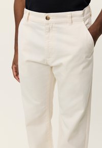 Μπεζ βαμβακερό παντελόνι με κλασικό σχέδιο, ίσια γραμμή, μπροστινές τσέπες και κλείσιμο με ένα κουμπί στη μέση.