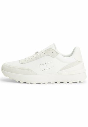 Zapatillas blancas con una mezcla de materiales lisos y texturizados, con un logo en el lateral y una suela gruesa y estriada para mayor tracción.