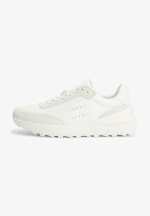 Zapatillas blancas con una mezcla de materiales lisos y texturizados, con un logo en el lateral y una suela gruesa y estriada para mayor tracción.