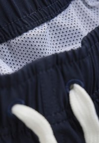 Jūreivio šortai su balta tinkline pamušalu. Yra elastingas liemuo, balta raištelių sistema ir daugybė siuvimo detalių, užtikrinančių patvarumą.