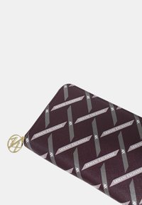 Portafoglio bordeaux con chiusura zip e texture goffrata, caratterizzato da un motivo ripetuto in grigio e bianco con il logo "Armani Exchange" e accessori in oro.