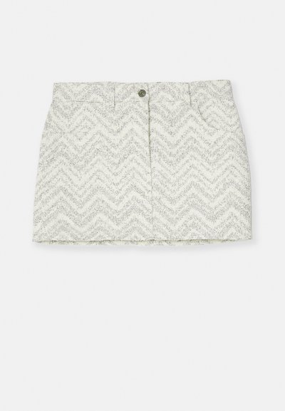 Jupe blanche avec un motif en chevrons gris, dotée d'une fermeture à boutons, de deux poches latérales et d'une coupe droite. Fabriquée en tissu texturé.
