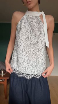 Hvid blomstret blondetop med en nøglehuldesigne, halterneck-bindebånd og frynset kant. Nedenfor supplerer en denimnederdel outfittet.