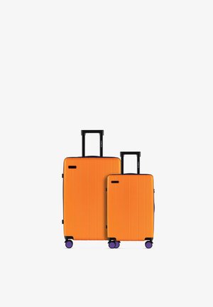Two upright orange suitcases with black handles and purple wheels, one large and one medium-sized, on a white background.