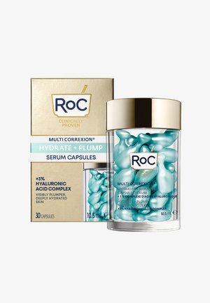 Ein transparenter Behälter hält 30 turkise Serumkapseln mit glatter Oberfläche. Goldene Akzente auf der Verpackung zeigen Marken- und Produktdetails.